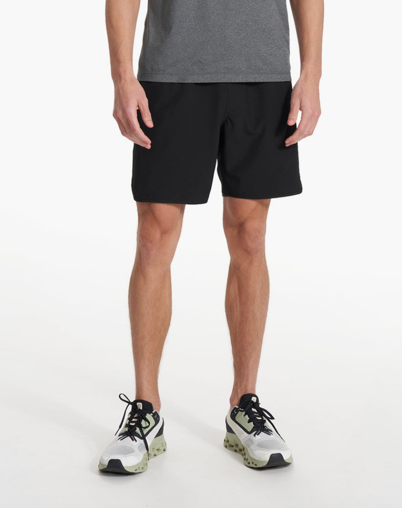A person standing and wearing Vuori Banks Shorts in a gray color with a drawstring waist and a 7-inch inseam.